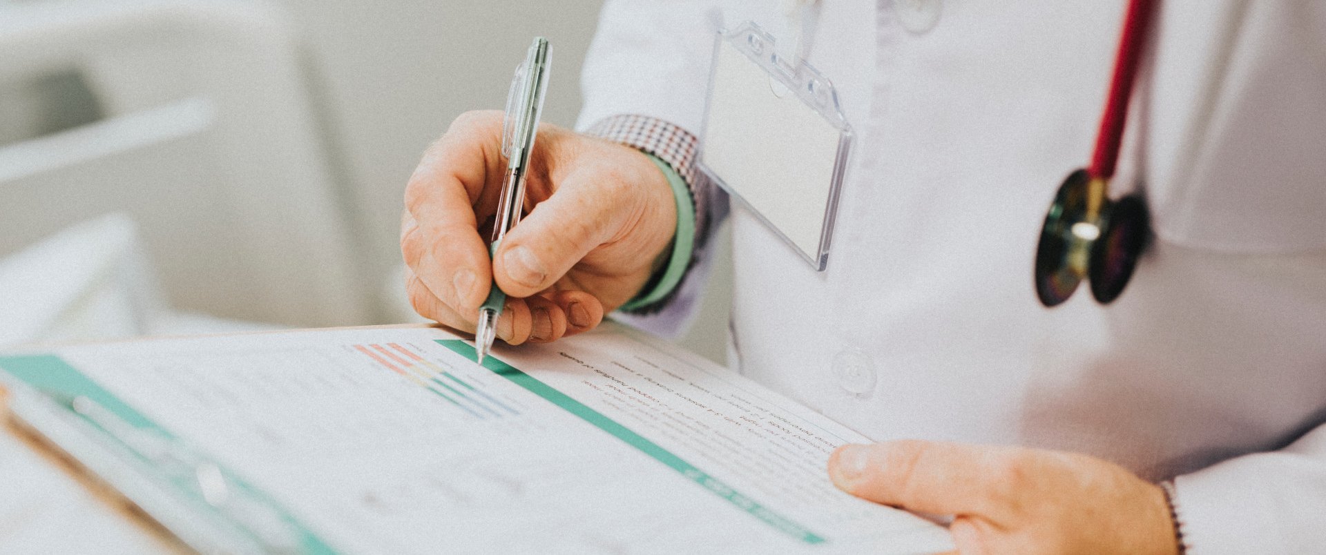 Doctor writing on chart attached to clipboard — Medical & Dental Services