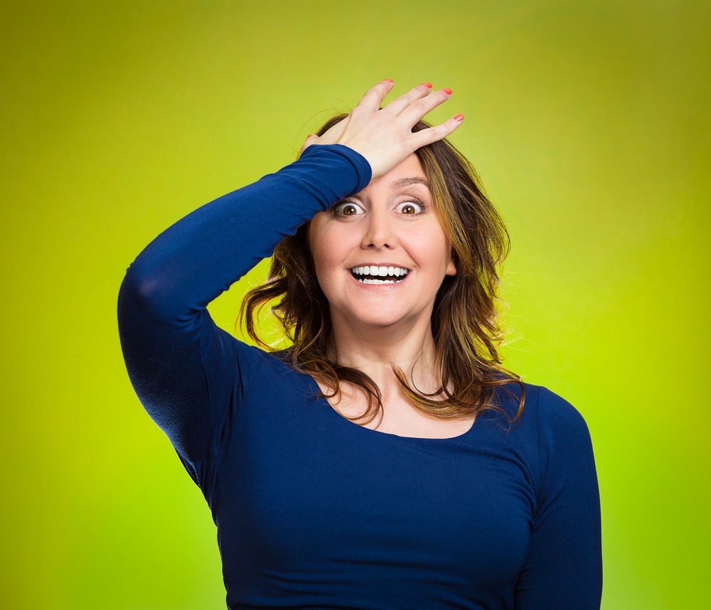 Closeup portrait excited young middle aged woman placing hand on head, palm on face gesture in duh moment, isolated green background. Human emotion facial expression feelings, body language, reaction.jpeg